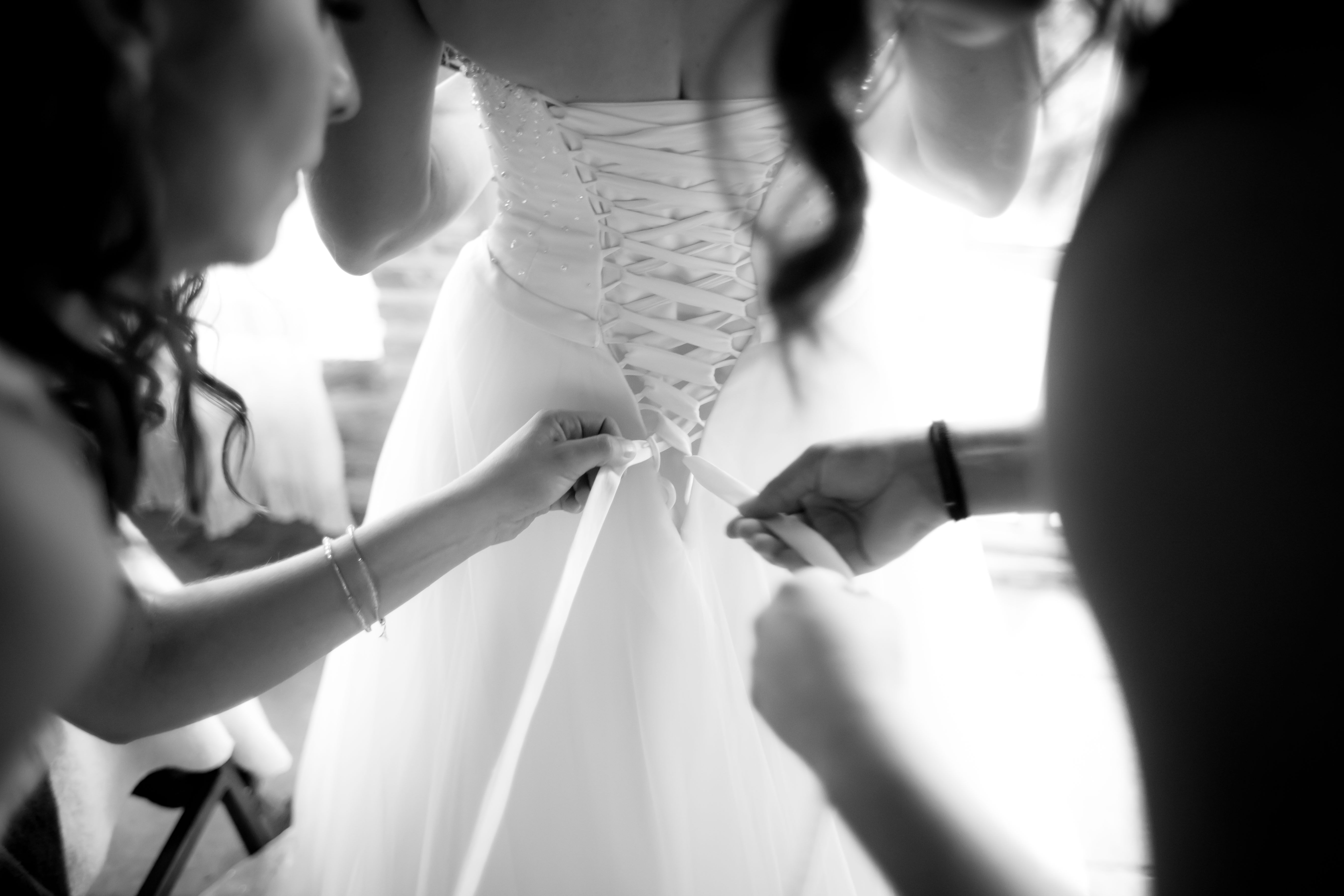 Black-and-white close-up of a bride’s corset wedding gown being laced up, Strictly Weddings Laveen AZ